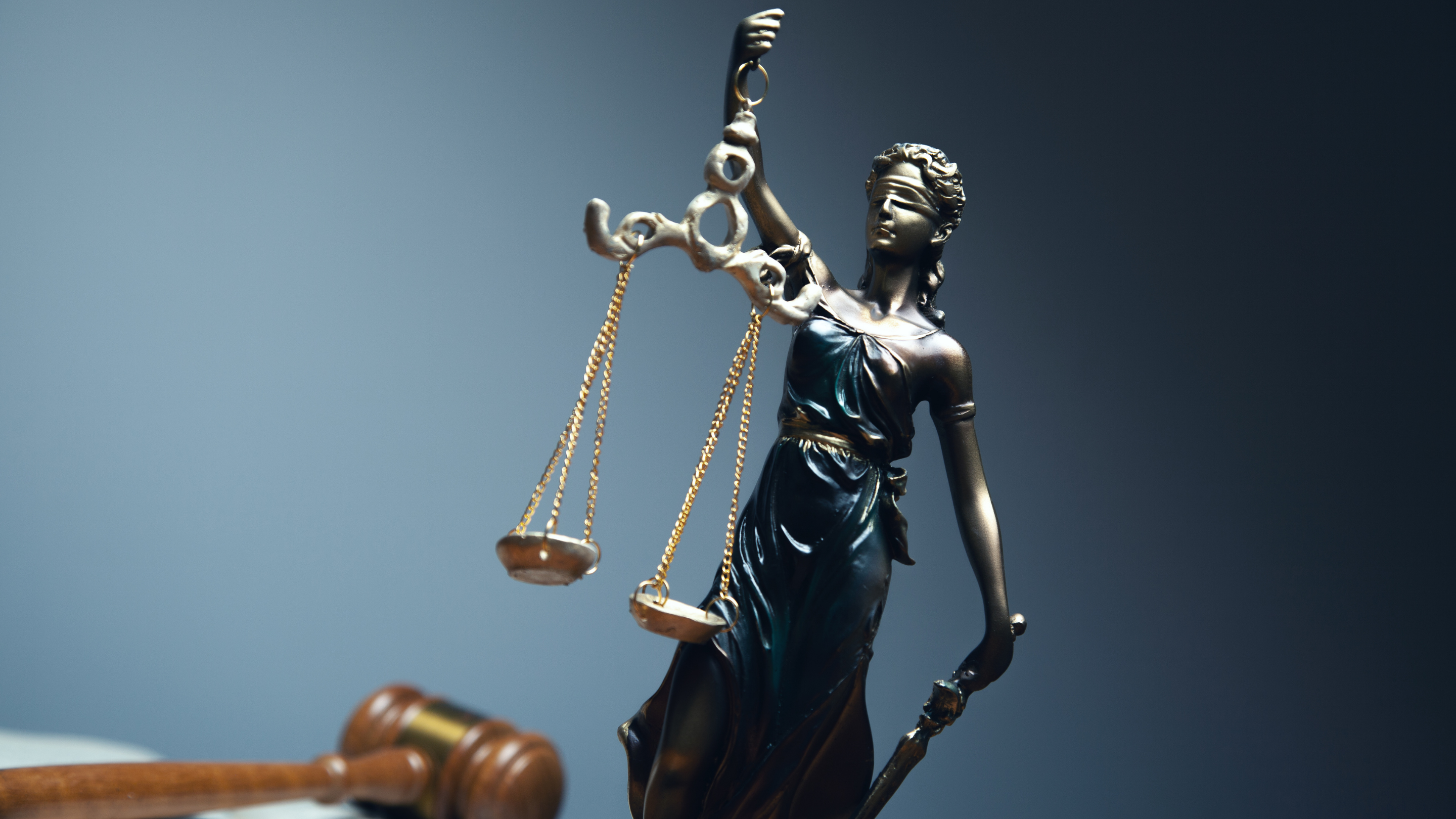 Photo of a blindfolded Lady Justice holding a balance and sword with a gavel in the foreground