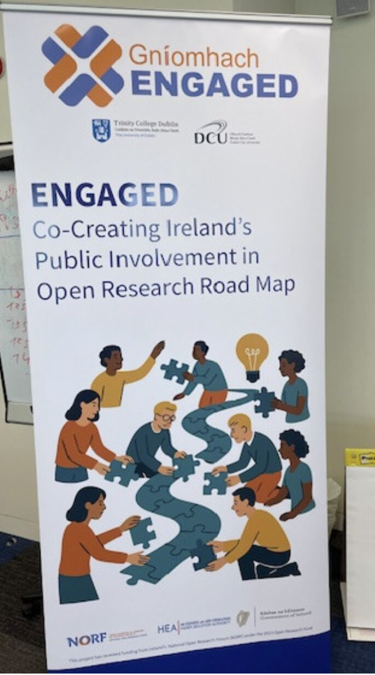 ENGAGED pull-up banner with 'Co-Creating Irelands Public Involvement in Open Research Road Map' printed on it and images of diverse cartoon people building a road with jigsaw pieces.