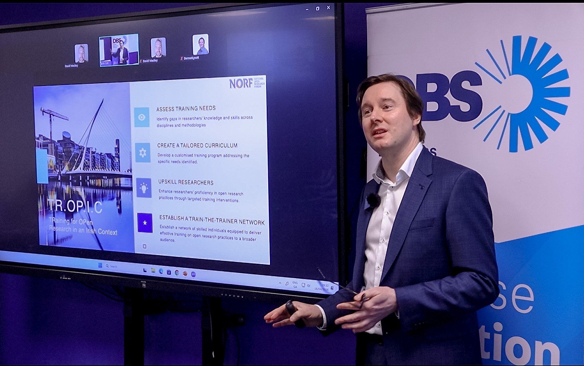 Dr Dermot Lynott of the Irish Reproducibility Network and TROPIC project presenting at Dublin Business School, with presentation materials featured on a screen to his left. Image credit: DBS.